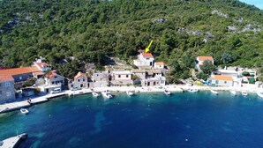 Un village côtier aux bâtiments en pierre, doté d’un port de plaisance et bordé d’eaux d’un bleu limpide.