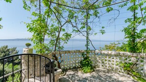 A balcony with a stone railing, a view of the sea, and a lattice fence. - Villa Kosa - Standard Double Room With Balcony and Sea View (Soba 1-Matija) (Brela)