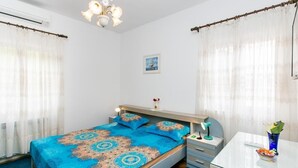Une chambre à coucher avec un lit, une table de chevet, une lampe et une petite table sur laquelle se trouve un vase avec des fleurs.