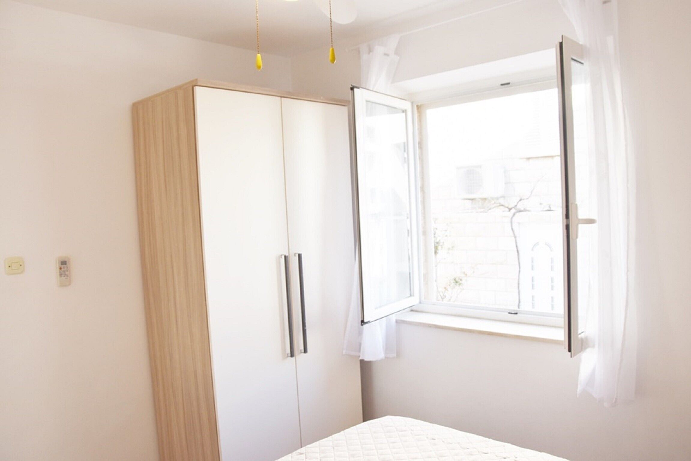 A bedroom with a bed, a wardrobe, and a window with curtains.