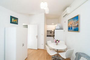 Una cucina moderna con mobili bianchi, un forno a microonde e un'area pranzo con tavolo e sedie bianche.