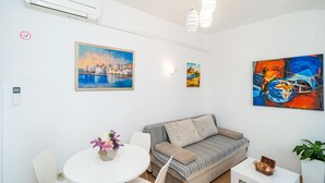 Un salon moderne avec un canapé, une table à manger et des chaises, ainsi que des œuvres d’art accrochées aux murs.
