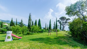 A grassy area with playground equipment, including a slide and swings, surrounded by trees and a clear sky. - Color Apartments - Comfort One Bedroom Apartment with Terrace and Partial Sea View (Mlini)