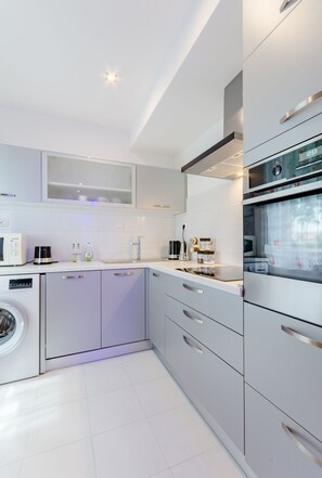 A modern kitchen with a washing machine, a coffee maker, and a microwave. - Studio Luce Mala (ST) - Studio with Terrace (Split)