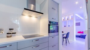 A modern kitchen with a built-in oven, a stainless steel range hood, and a white countertop. - Studio Luce Mala (ST) - Studio with Terrace (Split)