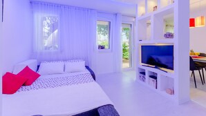 A modern bedroom with a bed, TV, and a dining area with a table and chairs. - Studio Luce Mala (ST) - Studio with Terrace (Split)