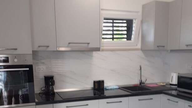 A modern kitchen with white cabinets, a black countertop, and a built-in oven.