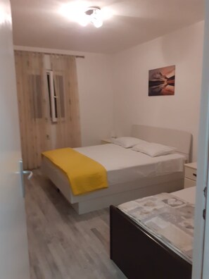 Una camera da letto con un letto, un comodino, tende a una finestra e un quadro appeso al muro.