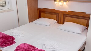 A double bed with white linens, two pink towels, and a wooden headboard. - Apartment Basic - One Bedroom Apartment (Dubrovnik)