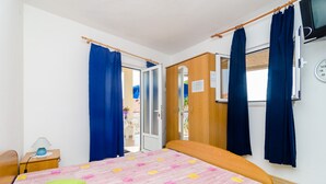 Une chambre à coucher avec un lit, une table de chevet, une armoire en bois et une fenêtre avec des rideaux.