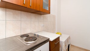 A kitchen with wooden cabinets, a stove, and a countertop. - Guest House Kiko - Studio (A3) (Pomena)