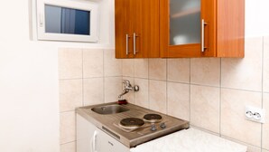 A small kitchen with a built-in stove, a window, and wooden cabinets. - Guest House Kiko - Studio (A3) (Pomena)