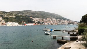 Un port de plaisance sur la côte, avec des bateaux amarrés, une vue sur la ville en arrière-plan et un paysage vallonné.