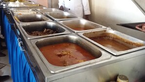 A buffet with multiple stainless steel serving trays containing various dishes.