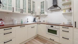 Una cucina moderna con mobili bianchi, una cappa in acciaio inossidabile e un piano di lavoro in legno.