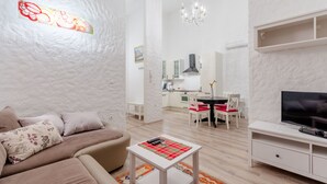 Un soggiorno moderno con un divano, un tavolino, una TV e un'area pranzo con sedie e tavolo.