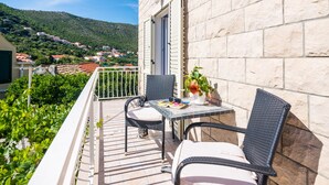 A balcony with wicker chairs, a table, and a potted plant.