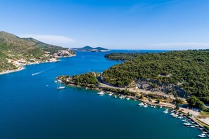 Vue aérienne d’une ville côtière avec un port de plaisance, des bateaux et de luxuriantes collines verdoyantes.