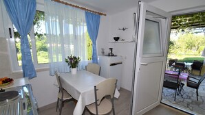 A dining area with a table and chairs, a potted plant, and a view of the outdoors. - Guest House Kanjuo - Studio Apartment with Terrace and Garden View (Mlini)