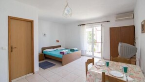 A small, well-lit room with a bed, a table with chairs, and a window.