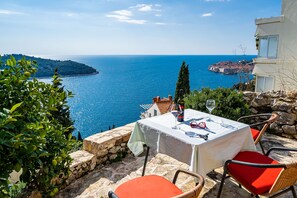 Ein Tisch im Freien mit Blick auf das Meer, Steinmauern und ein Gebäude im Hintergrund.
