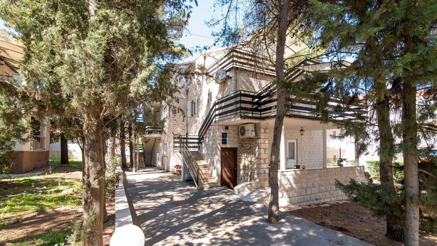 A stone building with a staircase leading to a balcony, surrounded by trees. - Apartments Pinija - Two Bedroom Apartment with Terrace (Supetar)