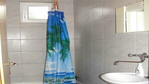 A bathroom with a toilet, a sink, and a shower curtain with a tropical design. - Apartments Pinija - Two Bedroom Apartment with Terrace (Supetar)