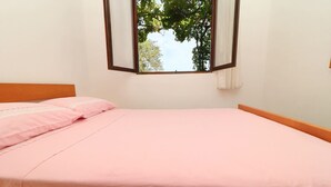 Een slaapkamer met een enkel bed, een raam met uitzicht op bomen en een witte muur.