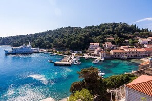 Uma vila costeira com um porto, barcos e edifícios com telhados vermelhos.
