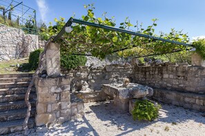 Une structure en pierre agrémentée d’une pergola, d’un escalier et d’un banc en pierre.
