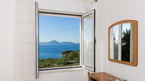 Ein Zimmer mit einem großen Fenster und Blick auf das Meer und die Berge.