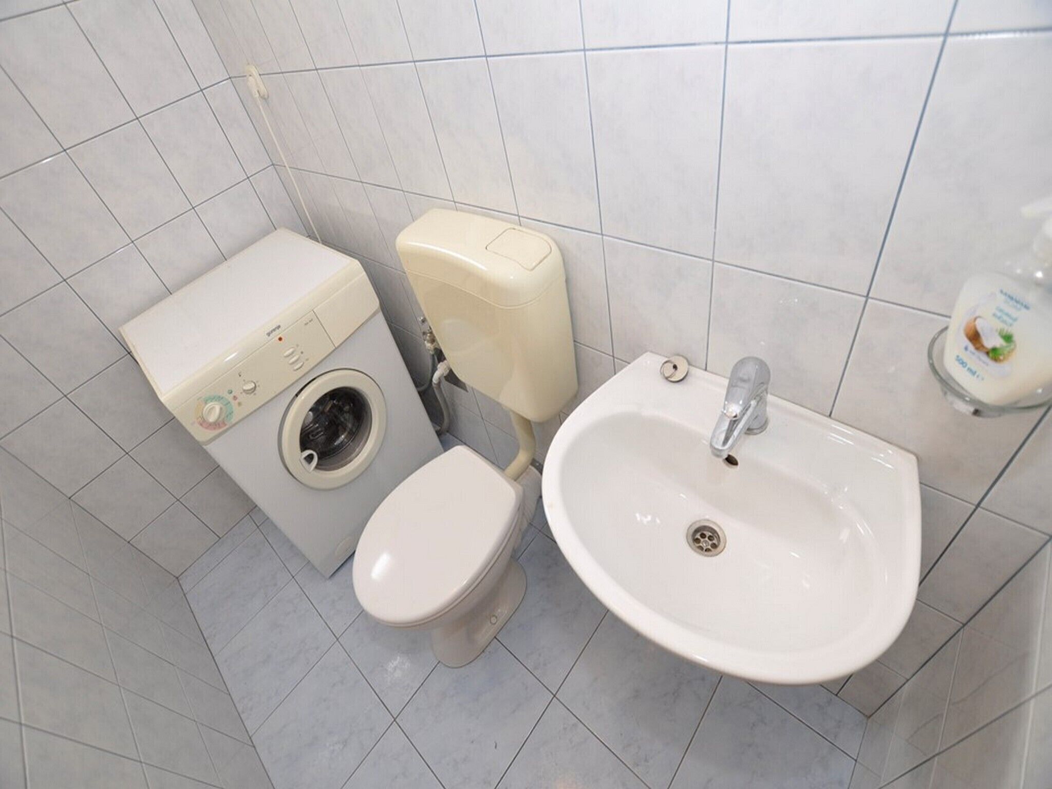 Een badkamer met toilet, wasmachine en wastafel.