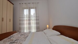 A bedroom with a bed, a wardrobe, and a window with curtains.