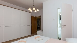 Une chambre à coucher comprenant un lit, une armoire, une porte et un luminaire suspendu.