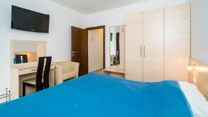 A bedroom with a bed, a desk, a chair, a wardrobe, and a television on the wall. - Villa Samba - Studio Apartment with Balcony and Sea View (Mlini)