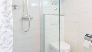 A modern bathroom with a glass-enclosed shower, a white toilet, and a wall-mounted heater.