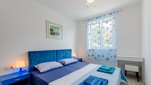 Un dormitorio con cama, mesitas de noche, un escritorio y una ventana con cortinas florales.