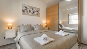 Ein modernes Schlafzimmer mit einem großen Bett, zwei Nachttischen mit Lampen, einem Spiegel und einem floralen Wandbild.