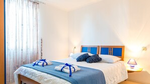Ein ordentlich gemachtes Bett mit blau-weißer Bettwäsche, einem blauen Kopfteil und einer Nachttischlampe.