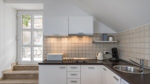 Una cucina moderna con mobili bianchi, un lavello in acciaio inossidabile e una macchina da caffè.
