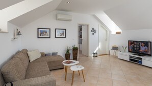 Un soggiorno moderno con soffitto alto, un divano, un tavolino da caffè e una televisione.