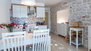 A compact kitchen with white cabinets, a tiled backsplash, and a stone wall.
