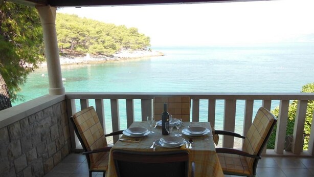 A table set for four with a view of the sea and a rocky coastline. - Apartment Sea Side - Two Bedroom Apartment with Sea View Terrace (ST) (Postira)