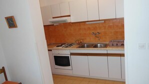 A compact kitchen with white cabinets, a stove, a sink, and a dishwasher. - Apartment Sea Side - Two Bedroom Apartment with Sea View Terrace (ST) (Postira)