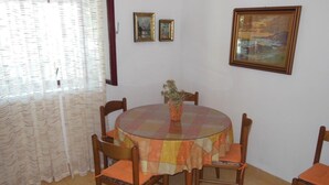 A dining area with a round table, six wooden chairs, and a vase with flowers. - Apartment Sea Side - Two Bedroom Apartment with Sea View Terrace (ST) (Postira)