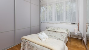 A bedroom with a bed, a bedside table, a lamp, and a window with sheer curtains. - Apartment Rea-Three Bedroom Apartment with Sea View (Dubrovnik)