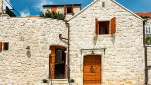 A stone building with a central entrance, a small balcony, and a wooden door. - Villa Kanada - Two-Bedroom House with Terrace and Sea View (Brsecine)