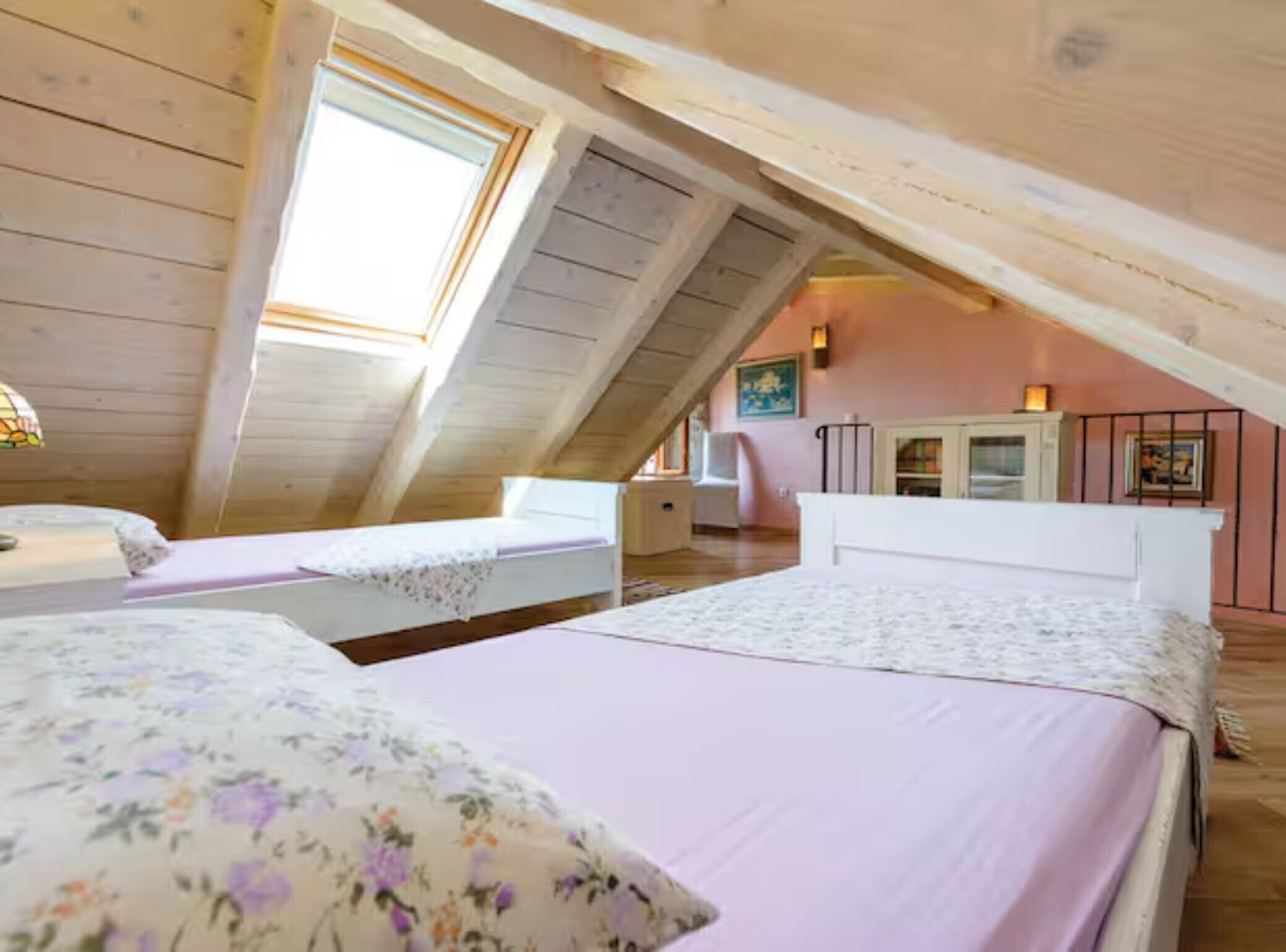 A room with two beds, a desk, a chair, a window, and a staircase leading to an upper level.