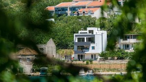 Un edificio moderno con tetto piatto, circondato da vegetazione lussureggiante e una superficie d'acqua.