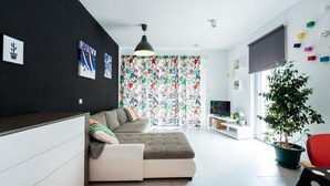 Un soggiorno moderno con un divano componibile, una TV e una pianta.